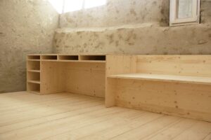 Ausgebauter Raum mit Bruchsteinwand, Holzboden und Einbauregalen