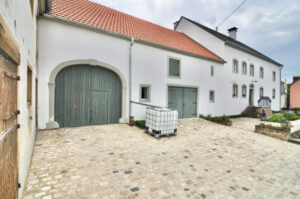 White farmhouse with courtyard and green gate in the Eifel