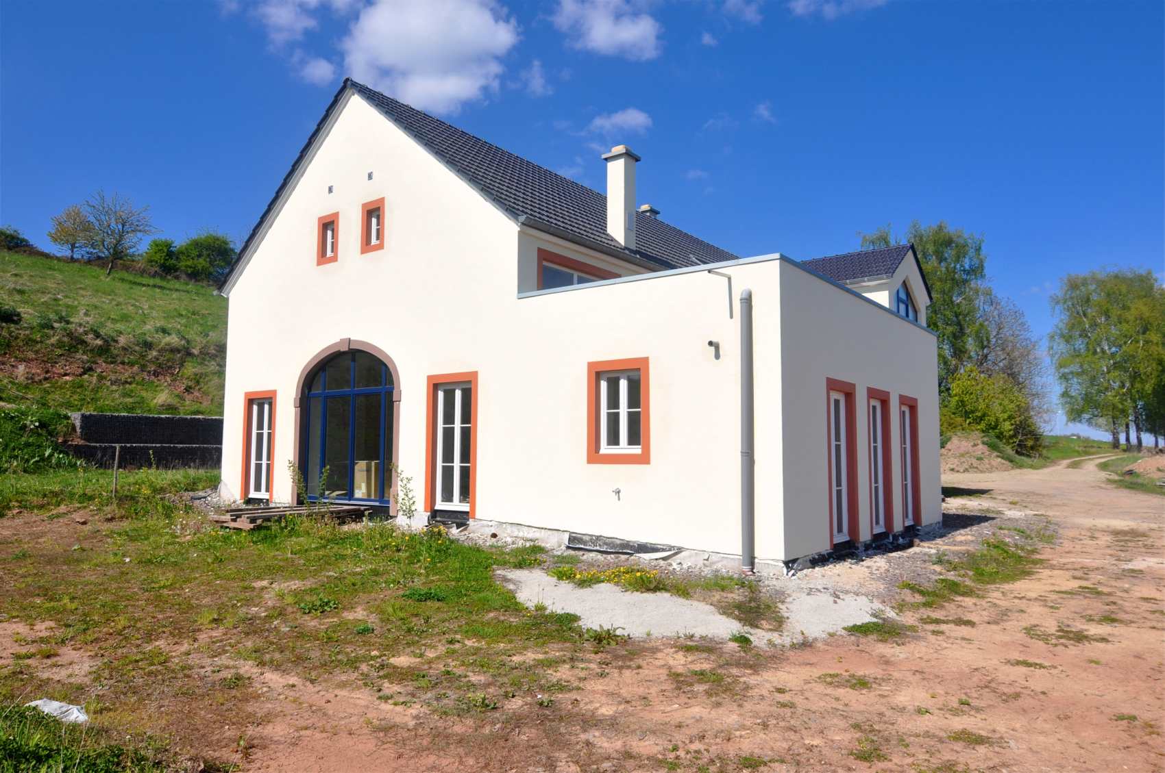 Weiß verputztes Haus mit Satteldach bei Sonnenschein