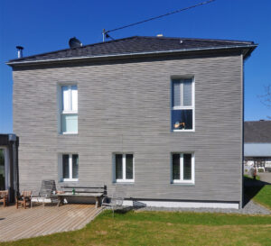 Bâtiment à deux étages avec façade en bois verticaux ternes