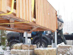 Holzbrücke wird per Kran auf Steinfundamente gesetzt
