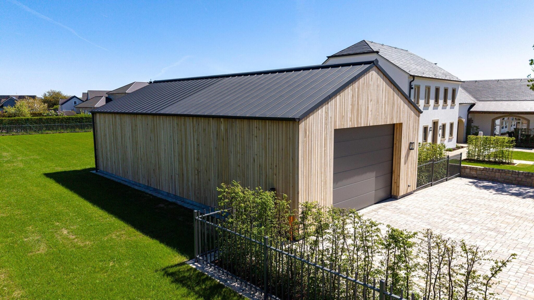 Garage mit Holzfassade und Pultdach neben einem Wohnhaus