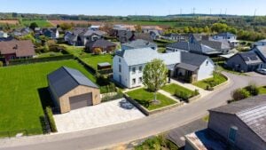 Luftaufnahme einer Neubausiedlung mit weißem Wohnhaus und Garage mit Holzfassade