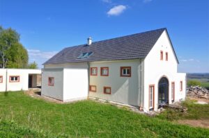 Weißes Wohnhaus mit Schieferdach auf einer Wiese in der Eifel