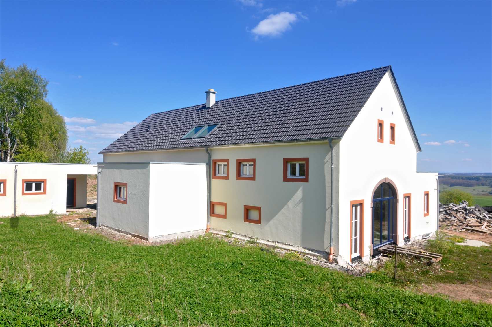Weißes Wohnhaus mit Schieferdach auf einer Wiese in der Eifel