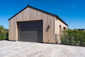 Garage in Holzrahmenbau mit vertikaler Holzfassade und grauem Garagentor