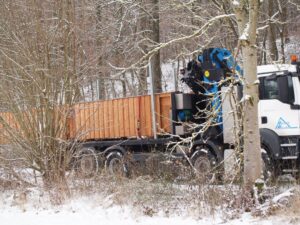 Lkw mit Ladekran liefert Holzbauteile im verschneiten Wald