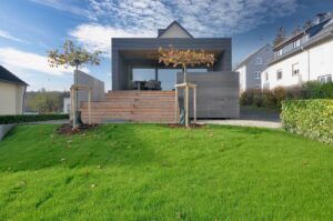 Modernes Holzhaus mit dunkler Holzfassade und Dachterrasse im Grünen
