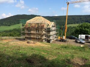 Rohbau mit neuem Holzdachstuhl und Kran auf der Baustelle