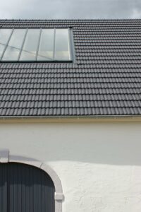 Neu eingedecktes Dach mit Dachfenster über weißer Fassade