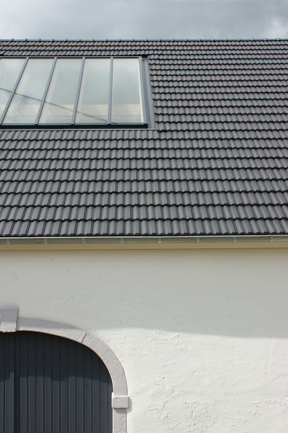 Neu eingedecktes Dach mit Dachfenster über weißer Fassade
