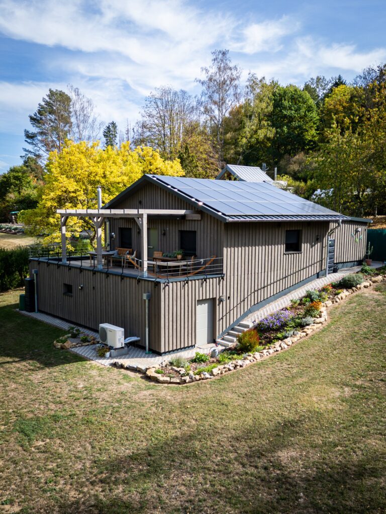 Holzhaus Bollendorf aus der Luft: Holzfassade, Terrasse mit Pergola und Solardach