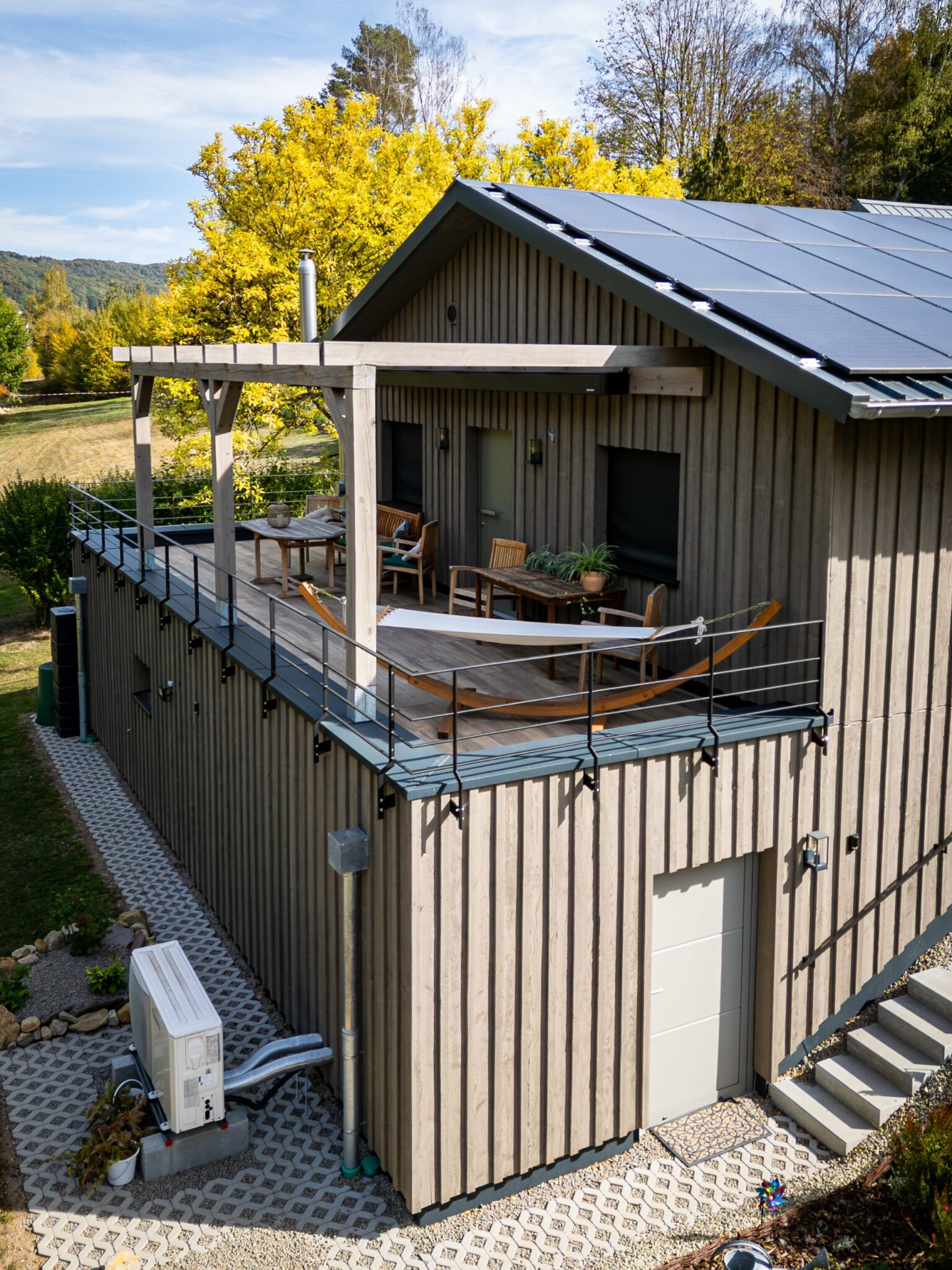 Luftaufnahme des Holzhauses Bollendorf mit Terrasse auf dem Sockelgeschoss