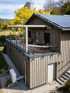 Luftaufnahme des Holzhauses Bollendorf mit Terrasse auf dem Sockelgeschoss