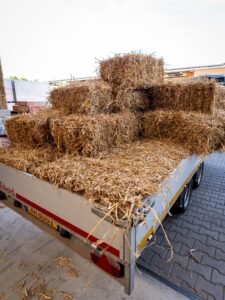 Strohballen auf einem Anhänger vor der Abbundhalle