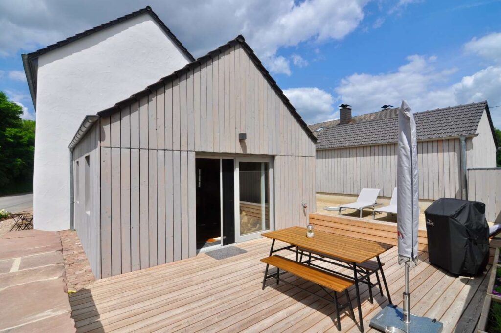 Anbau aus Holz mit grauer Lärchenschalung und Terrasse