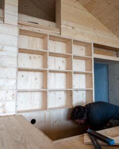 Zimmerer beim Innenausbau vor dem Einbauregal